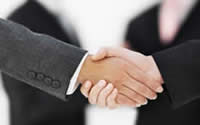 Two people in business suits shaking hands.