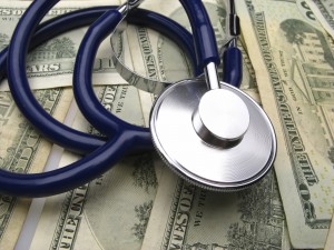 A stethoscope on a pile of dollar bills.
